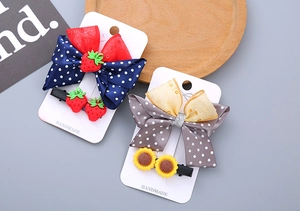 Detail view of handmade polka dot bow hair clips with resin strawberry and sunflower decor