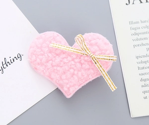 Detail of pink plush heart clip with striped bow and soft teddy fleece texture