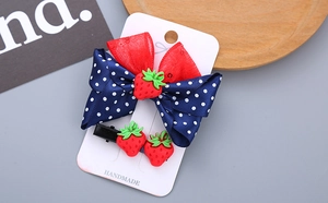 Detail of girls' blue polka dot bow hair clips with cute red resin strawberry accents