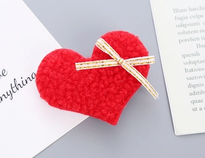Detailed macro view of a red plush heart hair clip with fuzzy lamb wool and white bow