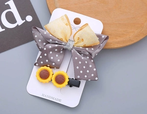 Detailed view of handmade bow hairpin with polka dots and sunflower hair clips on card