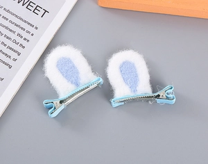 Close-up of white plush bunny ear hair clips with light blue ribbon details for girls
