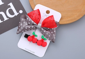 Detail of red cherry and polka dot ribbon bow hair clips set on handmade display card