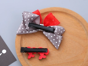 Detail view of two resin bow hair clips with polka dots and red metal duckbill clips