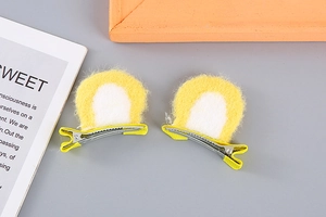 Close-up of cute plush bear ear hair clips with yellow fabric and metal alligator clips
