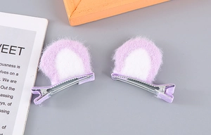 Detail of two plush cat ear hair clips with light purple faux fur and metal alligator clips
