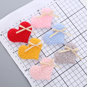 Plush heart-shaped hair clips with ribbon bows in various soft pastel colors