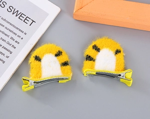 Detailed view of plush tiger ear hair clips for girls with soft yellow and white texture