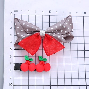 Two-piece girls hair clips set featuring red polka dot bow and resin cherry decorations
