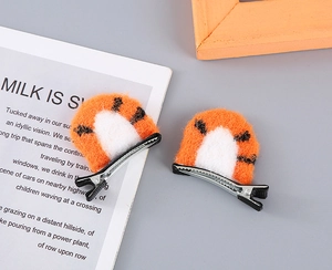 Detailed shot of plush orange tiger ear hair clips with black stripes on grey background