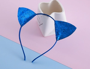 Détail d'un serre-tête oreilles de chat bleu scintillant sur fond rose et bleu