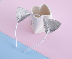 Détail d'un serre-tête oreilles de chat fait main avec paillettes argentées sur pastel