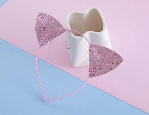Détail de serre-tête oreilles de chat rose pailleté montrant la texture brillante sur support