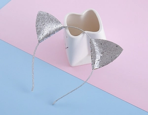 Détail d'un serre-tête oreilles de chat pailleté argenté sur un support décoratif