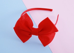 Macro view of the large red satin bow headband with fine ribbed fabric texture for girls