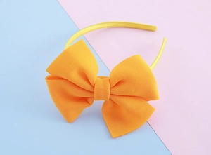 Detail of a bright yellow fabric bow headband for girls on a pastel blue and pink background