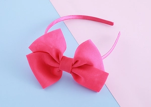 Detailed view of large rose red fabric bow headband with glossy silk texture finish