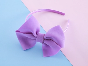 Detail of the large purple bow headband showing rich fabric texture and satin wrap finish