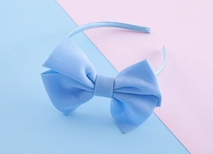Close-up detail of the light blue satin oversized bow headband with fine fabric texture