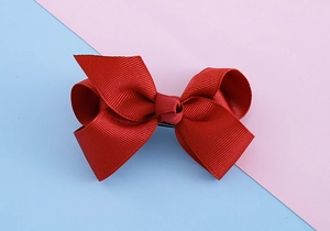 Detailed view of red grosgrain ribbon bow hair clip with high-density woven texture