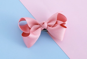 Detailed view of pink grosgrain ribbon bow hair clip with textured fabric and duckbill clip