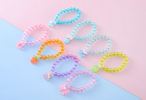 Detail of colorful kids beaded bracelets with glittery strawberry and animal pendants