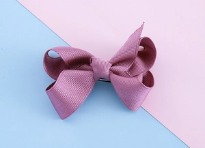 Detailed close-up of double-layered morandi purple ribbon bow hair clip on pink background
