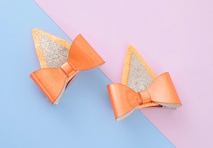 Gros plan de barrettes oreilles de chat à paillettes orange avec nœud et clip métal