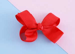 Detailed close-up of handmade red grosgrain ribbon bow clip for children