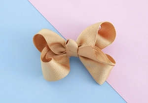 Detail of champagne gold grosgrain ribbon bow hair clip with textured ribbed fabric