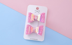 Détail de pinces à cheveux à nœuds roses pailletés pour filles sur carte cadeau