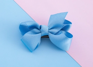 Close-up of sky blue grosgrain ribbon hair bow with layered design and fabric texture