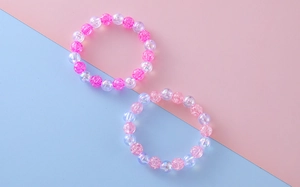 Detail of sweet beaded bracelets with crackle texture beads in pink and purple colors