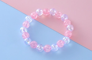 Detail showing pink crackle beads and iridescent purple pearls on a girl's beaded bracelet
