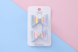 Détail de barrettes à cheveux nœud pailleté bleu clair sur carte avec fond pastel doux
