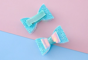 Détail de barrettes bleu clair pailletées avec centre holographique et pince en acier