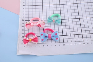 Detail view of 4cm handmade ribbon bow hair ties on a grid measuring paper for kids