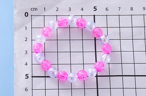 Detailed macro view of pink crackle beads and iridescent pearls on 6cm elastic bracelet