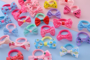 Detailed close-up of kids bow hair ties with floral and polka dot patterns on pastel background