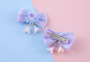 Détail d'une pince à cheveux nœud violet avec fleur en résine et perles de muguet