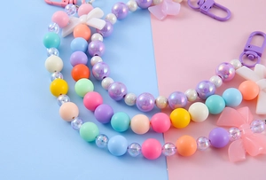 Close-up of pastel beaded keychain with colorful bows and iridescent floral accents