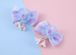 Détail de pinces à cheveux papillon en satin lavande avec fleurs et pompons