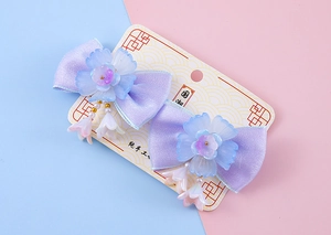 Détail de barrettes noeuds en satin violet avec accents floraux et franges de perles