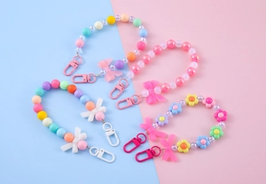Detail of macaron pastel beaded keychains with resin bows and floral charms for phone cases