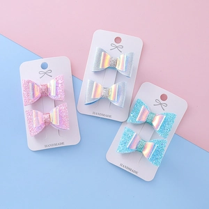 Trois paires de pinces à cheveux papillon pailletées pour filles sur cartes au fond rose doux