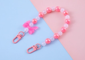 Detail of pink beaded lanyard with bow and flower charms for phone or bag decoration