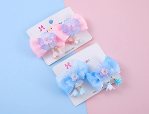 Détail de barrettes à nœuds en soie rose et bleu avec fleurs et pendentifs lys