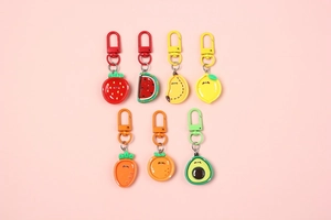 Flat lay of colorful resin fruit keychains featuring cute expressions and painted metal hooks