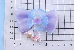 Détail d'un nœud papillon en soie lavande avec fleur en résine et pompons en perles