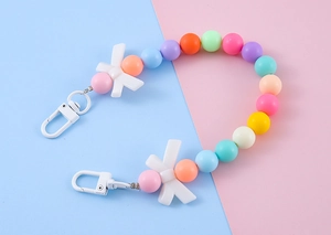 Detail view of colorful macaron beaded charm with white bows and lobster clasps